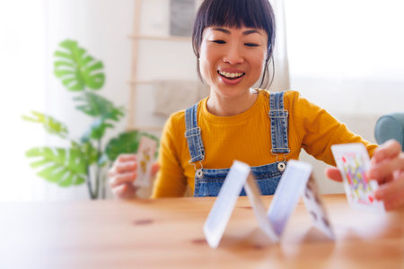 Mature Asian woman relaxing and enjoying leisure time at home, playing card games and stacking cards
