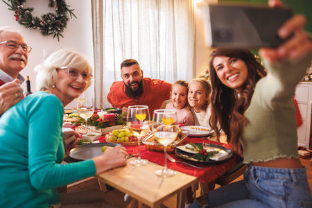 Multi-generation family gathered at home for Christmas dinner having fun taking selfies and enjoying...