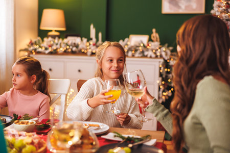Happy family gathered around the table, having Christmas dinner all together at home, mother making a toast with her daughtersの写真素材
