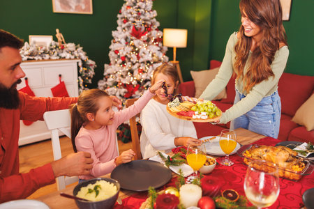 Young Caucasian woman serving food during family Christmas dinner at homeの写真素材