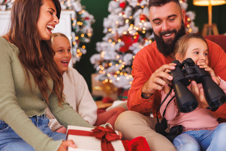 Young parents enjoying spending Christmas day with their children at home, having fun opening presentsの写真素材