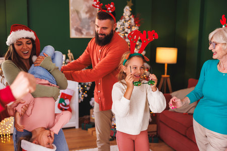 Multi-generation family having fun singing, dancing and playing while spending Christmas day all together at homeの写真素材