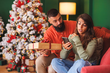 Young couple angry and sad having a fight while spending Christmas day together at homeの写真素材