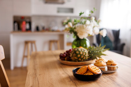 Dinning room table with cookies, muffins and fruit plate ready for breakfast at home in the morningの写真素材