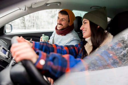 Cheerful couple in love having fun driving a car while travelling to a winter vacation road trip