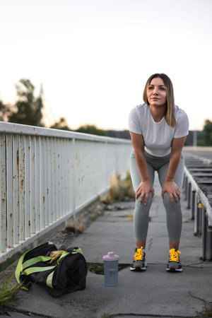 Active fit young woman in sportswear taking a morning jogging break, catching breath, exhausted
