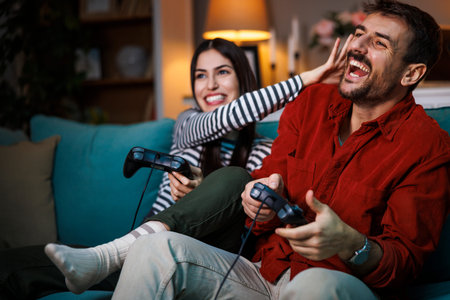 Beautiful young couple in love having fun playing video games while relaxing at home at night