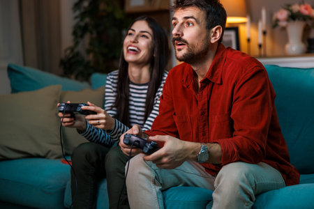 Beautiful young couple in love having fun playing video games while relaxing at home at night