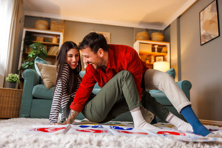 Beautiful young couple in love having fun playing leisure balancing and flexibility game while relaxing at homeの写真素材