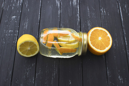 Jar of tasty fresh lemonade with lemon and orange in wooden black backgroundの写真素材