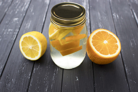 Jar of tasty fresh lemonade with lemon and orange in wooden black backgroundの写真素材