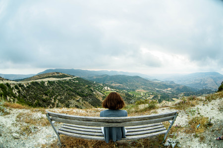 Woman sitting on bench in mountainsの写真素材