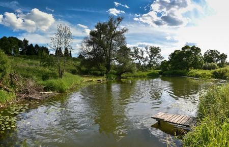 Pier on a calm river in the summer. Wooden pier bridge in the morning. Place for fishing in the river.の写真素材