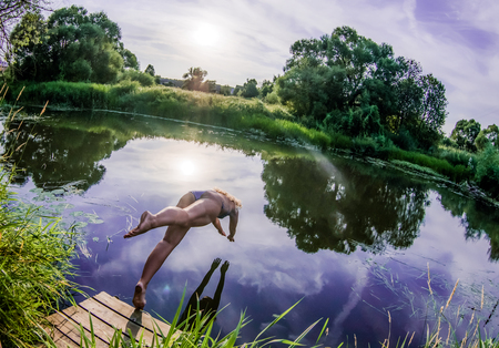 Girl diving from the bridge in waterの写真素材