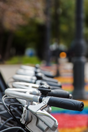 Row bicycle handle bar and bell close-up, image of a bicycle rental in the city park sidewalk. Healthy, ecological transport conceptの写真素材