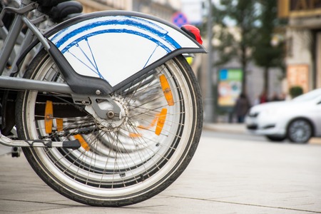Healthy, ecological transport concept. Rental bikes parking lot. Row bicycle wheels in the city sidewalkの写真素材