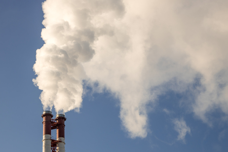 industrial factory pipes smoke at the sun on blue sky. ecology problemsの写真素材