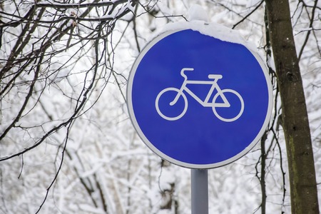 Bicycle lane, round blue road sign against tree branchesの写真素材