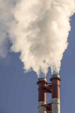 industrial factory pipes smoke at the sun on blue sky. ecology problemsの写真素材
