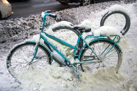 Heavy dirty snow covered parked bike in cityの写真素材