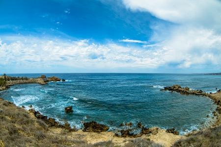 sea surface and sunny summer rocky coastline with cloudsの写真素材