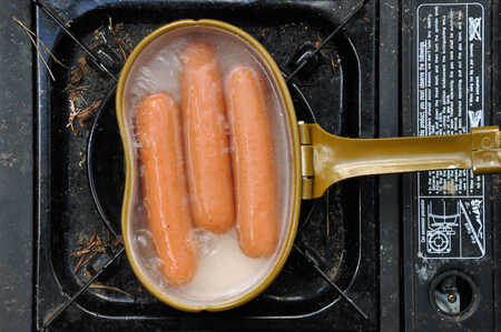 boiling hot dogs sausages in camping potの写真素材