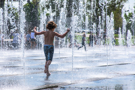 boy running between water flow in public park