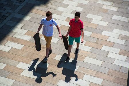 Russia, Moscow - May 13, 2018: Teenagers with skateboards and long shadow on the street of Moscowのeditorial素材