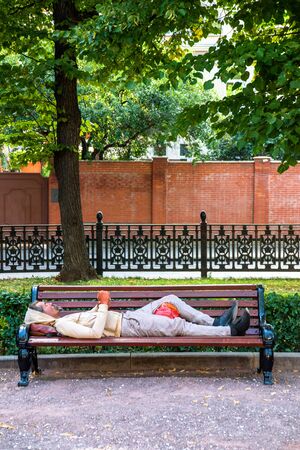 Russia, Moscow - 10 July, 2018. Lonely homeless sleep on the park benchのeditorial素材