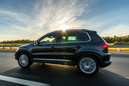 Black car on the road with sun and blurred speed effectの写真素材