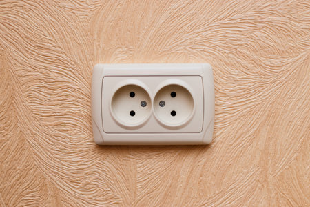 European electric outlet on wall covered with wallpaper