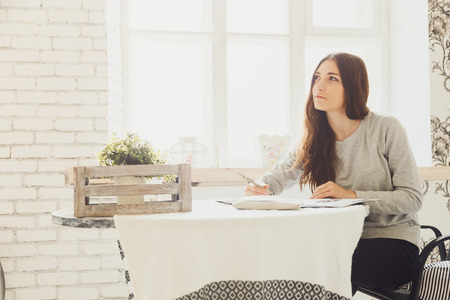 Young girl designer dreams sitting at a tableの写真素材