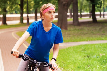 young beautiful woman riding a bicycle in a park. Active people. Outdoorsの写真素材