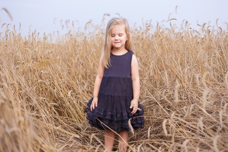 Cute happy little girl greams in wheat fieldの写真素材