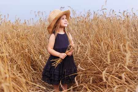 happy young woman in black dress and sun hat enjoying on cereal fieldの写真素材