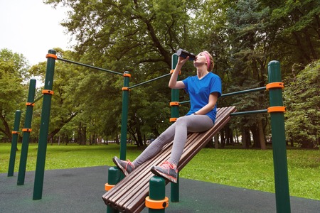 Young woman drinking water from plastic bottle after jogging. Healthy lifestyle.の写真素材
