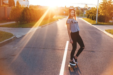 Young woman down the road with a skateboardの写真素材