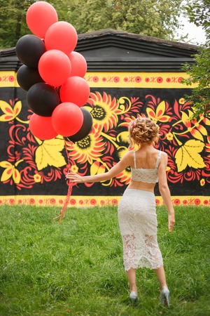 Back view of beautiful young woman in hat standing with balloonsの写真素材