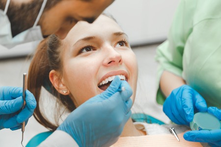 The dentist checks the condition of the teeth of a beautiful girl.の写真素材
