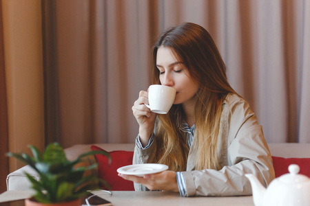 woman drinking coffee in the morning at restaurant soft focus. Closeup portrait of the pretty girl with cup of teaの写真素材
