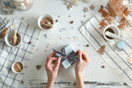 Woman bows tie in on christmas present with a blue ribbon. Holiday concept. Top view.の写真素材