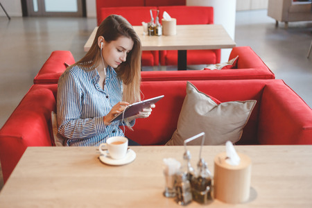 Candid image of a young woman using tablet computer in a cafeの写真素材