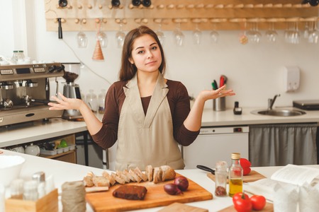 Young woman is preparing some food in the kitchen. She cutting a bread.の写真素材