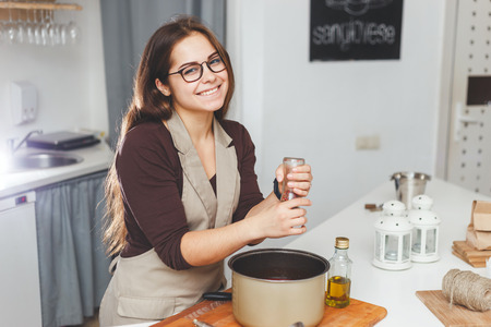 Happy female adds salt or spices into soup pan at the kitchenの写真素材