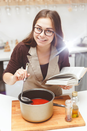 Young woman cooking soup in her kitchenの写真素材