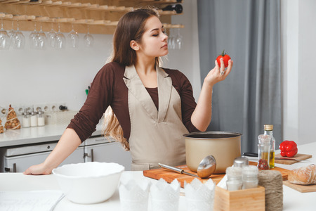 The hostess in the kitchen wants to cook diet dish with tomato.の写真素材
