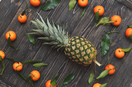 Pineapple and tangerines and a rustic wooden backgroundの写真素材