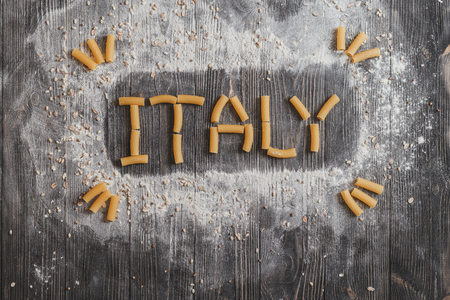 Lettering ITALY pasta on black aged rustic wooden background. Top viewの写真素材