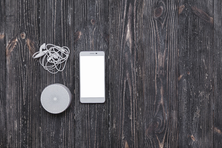 Portative sound system with earphones and mobile phone  blank screen on dark wooden tableの写真素材
