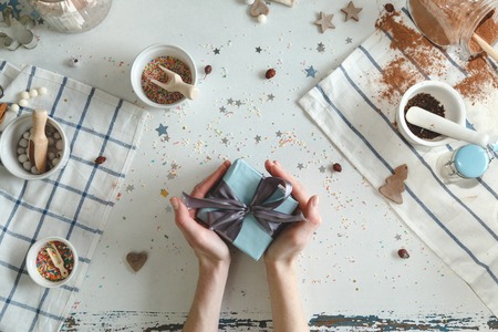 Creative hobby. Womans hands wrap holiday handmade present in craft paper with twine ribbonの写真素材